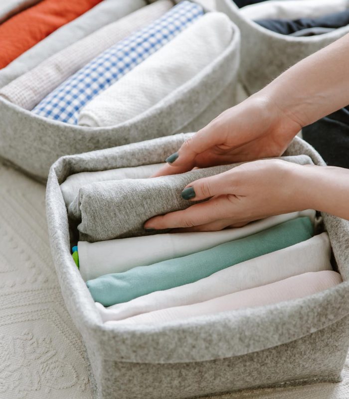 Woman folding clothes, organizing stuff in boxes and baskets. Co